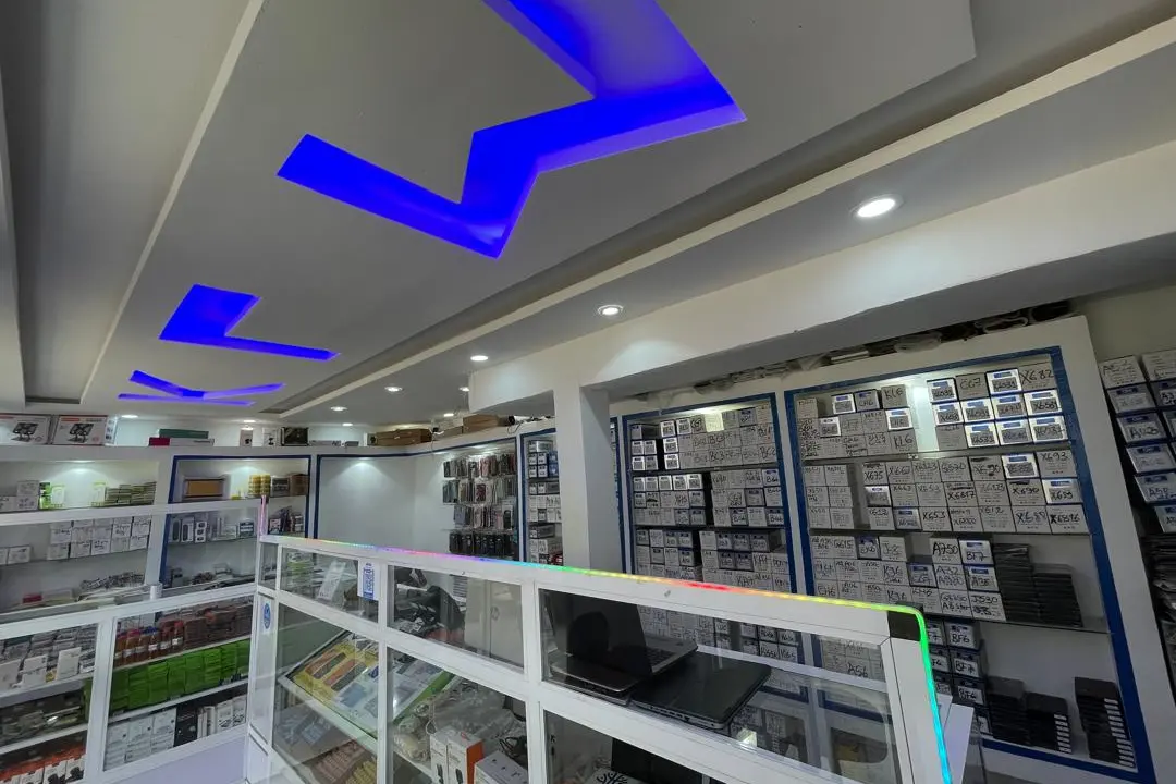 Intérieur de la boutique KLM-TECH : lettres KLM lumineuses au plafond, vitrines et mur de pièces de rechange étiquetées