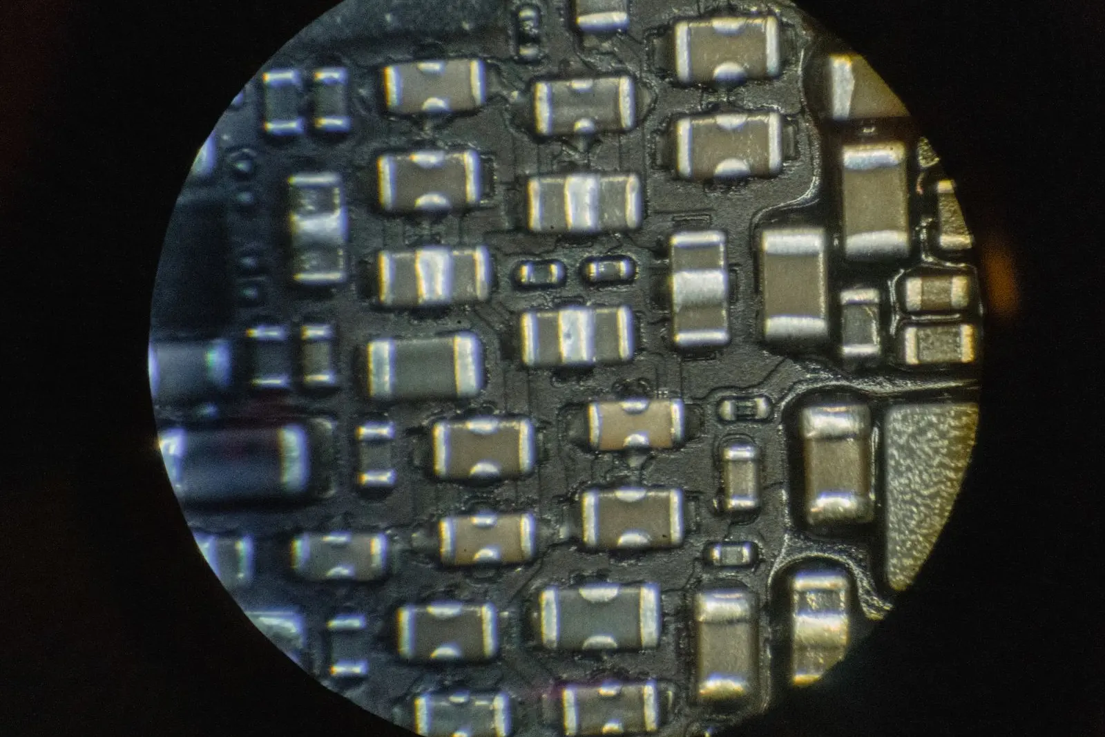Condensateurs et résistances d'une carte mère vus à travers l'objectif du microscope