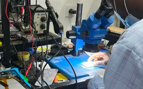 Technicien KLM-TECH au binoculaire, carte eclairee sous l'objectif