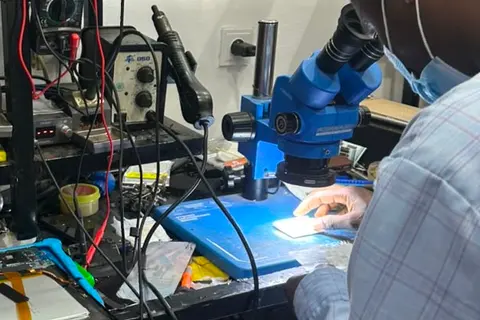 Technicien KLM-TECH au binoculaire, carte eclairee sous l'objectif